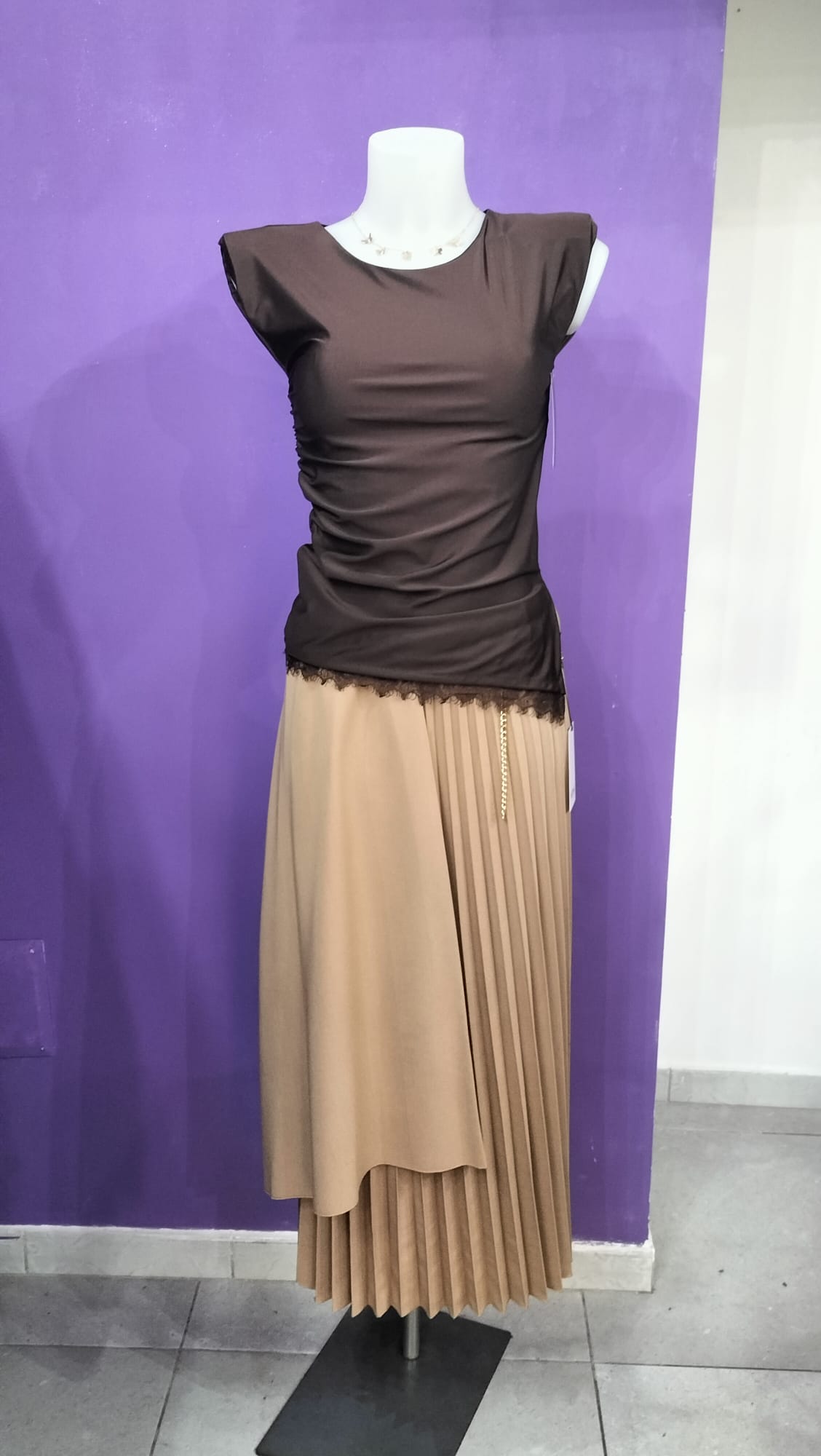 Gonna  Midi Plissettata, con silhouette asimmetrica a doppio strato che crea movimento e profondità visiva.