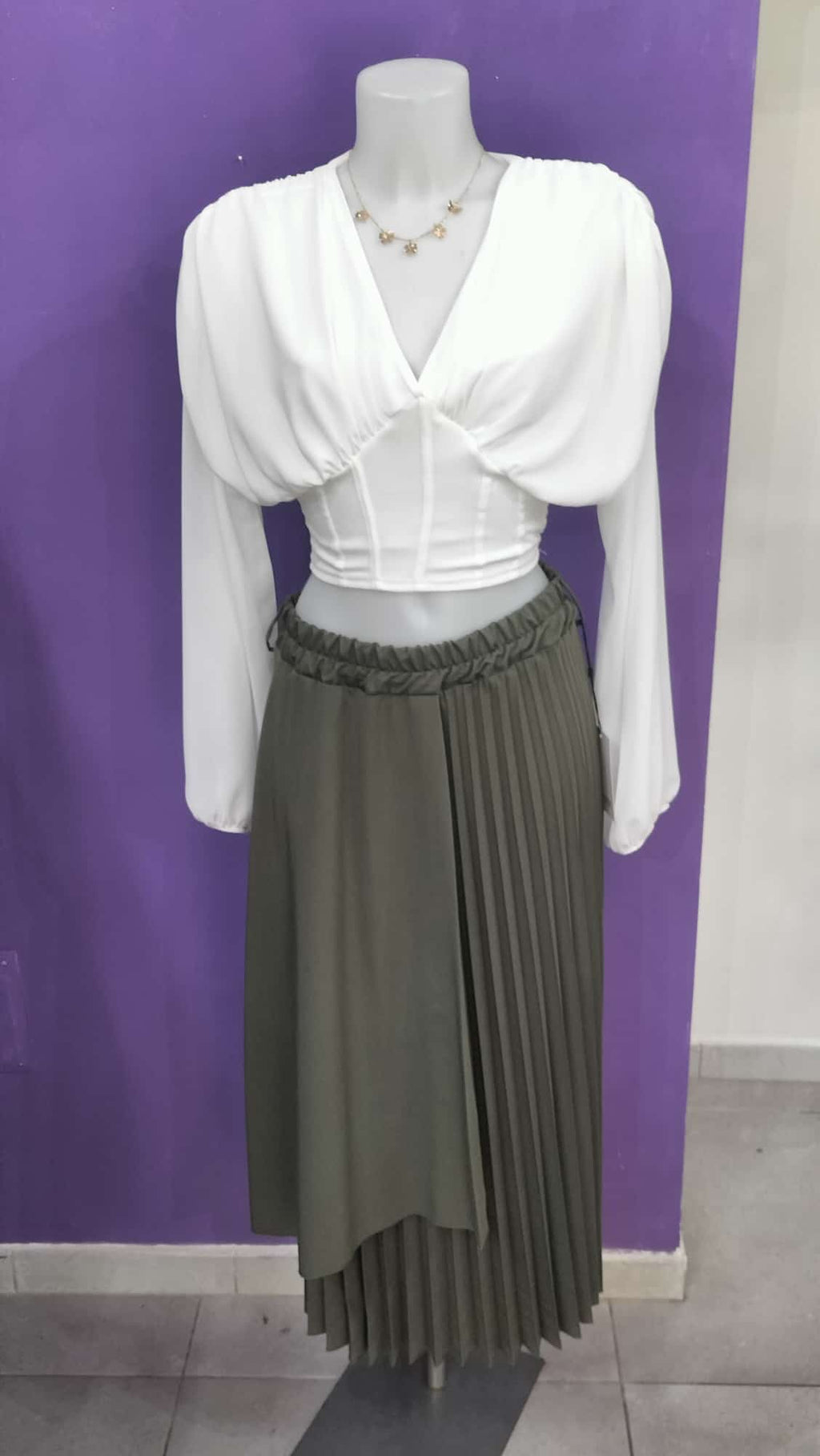 Gonna  Midi Plissettata, con silhouette asimmetrica a doppio strato che crea movimento e profondità visiva.