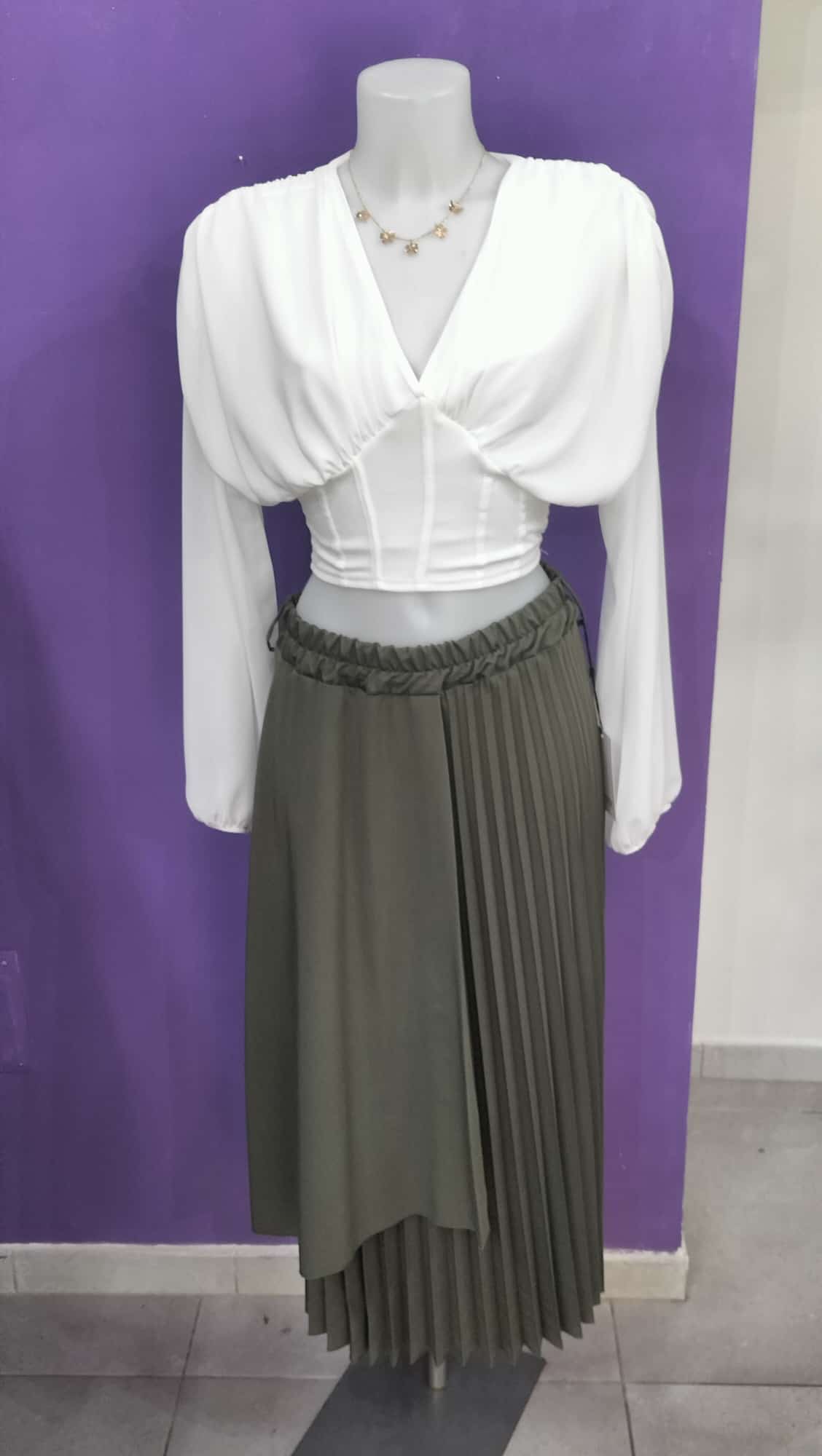 Gonna  Midi Plissettata, con silhouette asimmetrica a doppio strato che crea movimento e profondità visiva.