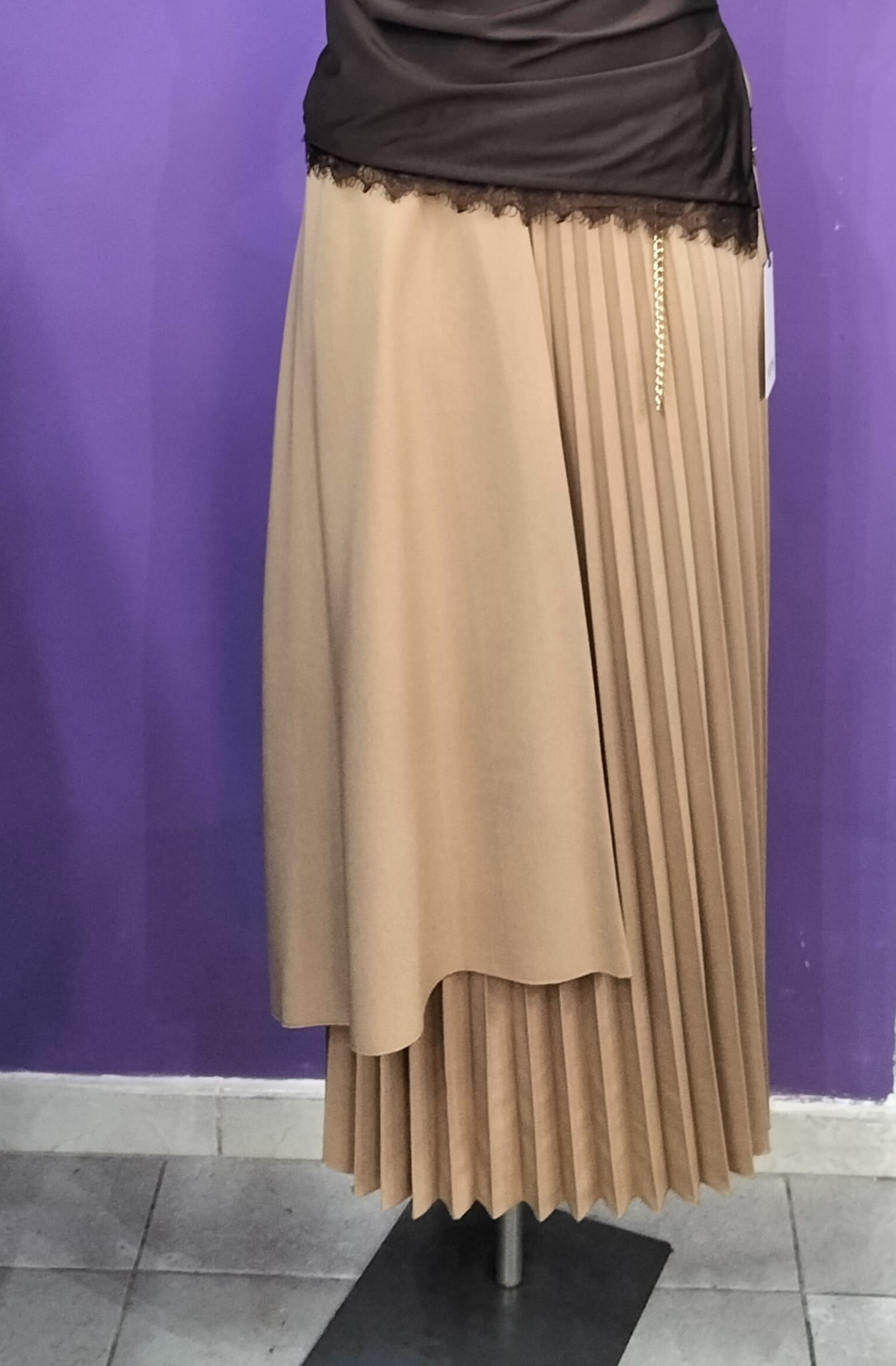 Gonna  Midi Plissettata, con silhouette asimmetrica a doppio strato che crea movimento e profondità visiva.